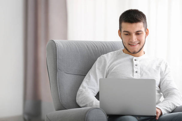 Молодой человек с современным ноутбуком дома
 - Фото, изображение