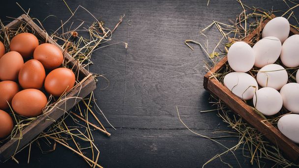 Chicken raw eggs in a wooden basket. On a wooden background. Top view. Copy space. - Foto, Bild