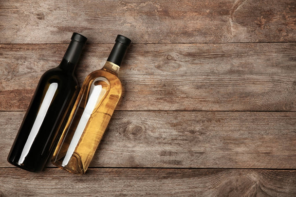 Two bottles with red and white wine on wooden background - Valokuva, kuva