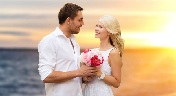 happy couple with flowers over sea background - Fotó, kép