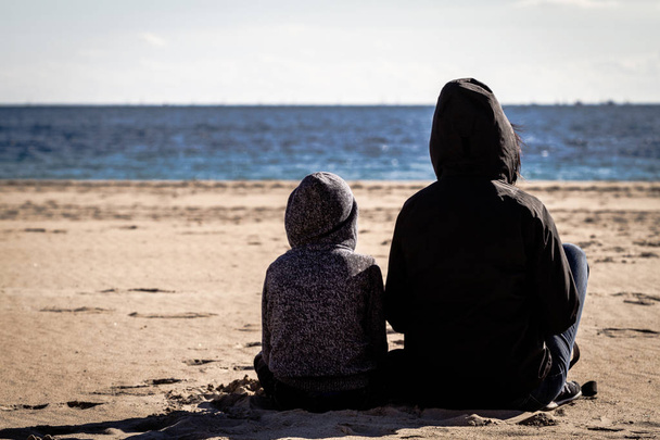 Fia, és az anya ül visszafordít-ra a strandon, és nézte a tenger - Fotó, kép