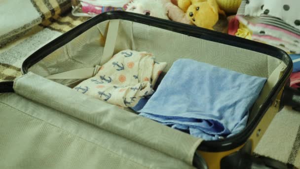 Mom and daughter are going on vacation. Two pairs of hands put things and toys in a travel bag. - Imágenes, Vídeo