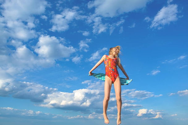 Girl in a swimsuit is jumping against the sky - Фото, изображение