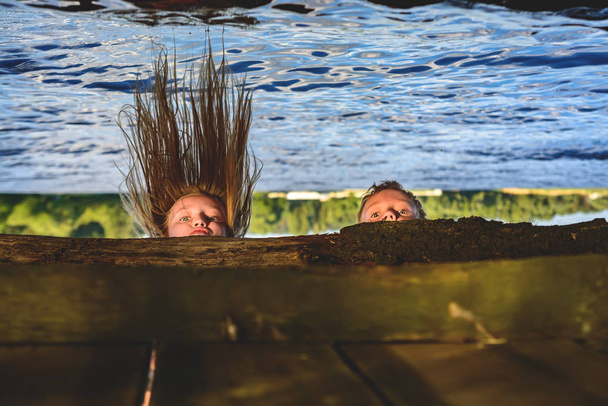 A boy and a girl are peering under a bridge over the water - Photo, Image