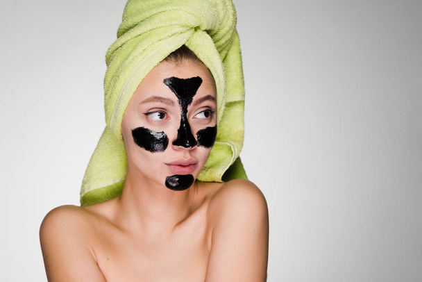 woman with a towel on her head applied a mask to problem areas of the skin of the face - Foto, afbeelding