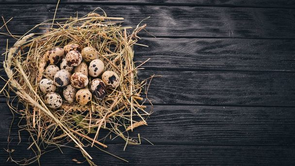 Quail eggs in the hay. On a wooden background. Top view. Copy space. - Photo, image