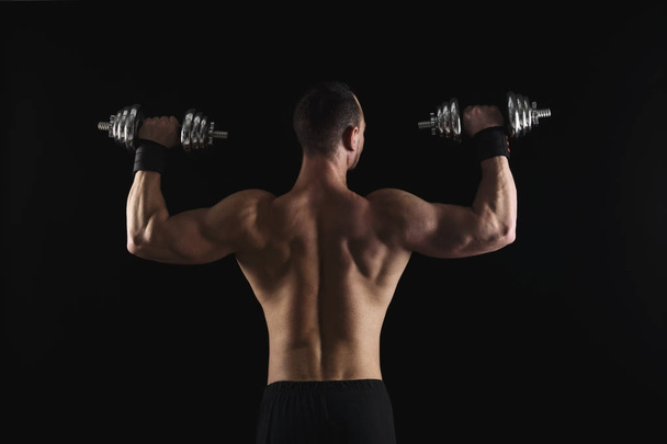 Forte uomo atletico con manubri mostra corpo muscolare nudo
 - Foto, immagini