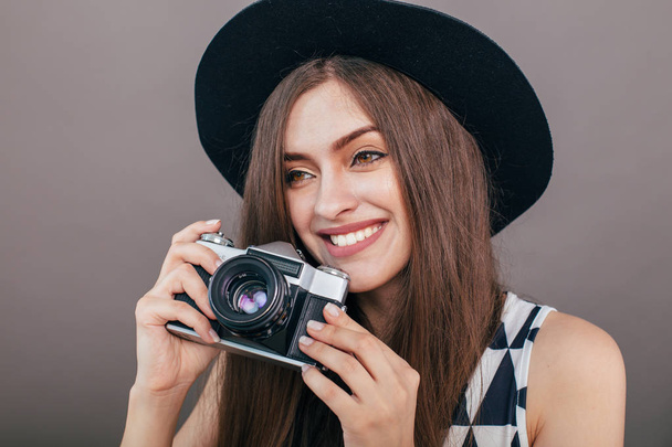 Stylish woman photographer with retro camera on the grey wall background. Image with copy space - Photo, Image