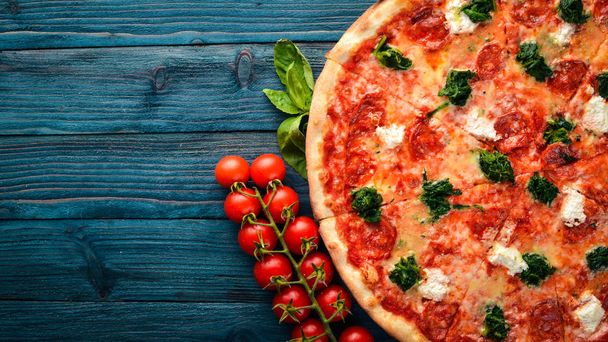 Neapolitan Pizza. Spinach, gorgonzola cheese, sausage salami. On a wooden background. Top view. - Foto, Imagen