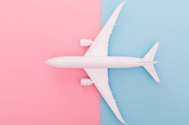 Miniature toy airplane on blue and rose background. Trip by airplane. Top view - Photo, Image