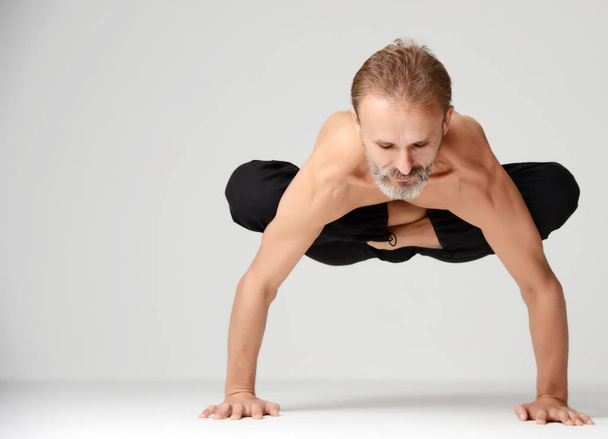 Man practicing yoga classic asana dance pose standing on hands - Foto, imagen
