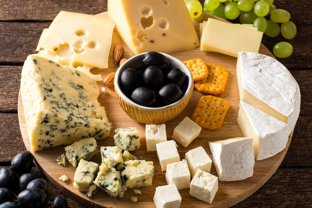 Various types of cheese on wooden cutting board. - Foto, Imagen