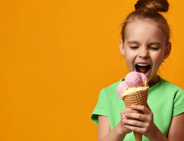 Pretty baby girl kid eating licking banana and strawberry ice cream in waffles cone - Foto, Imagem