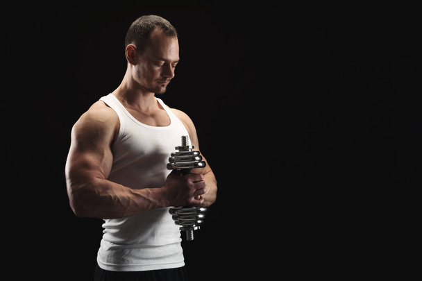 Strong athletic man with dumbbell showes muscular body - Foto, Bild