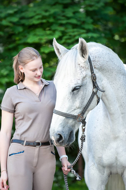 Pretty young teenage girl leads white horse - Photo, Image