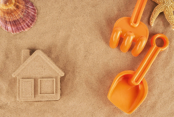 Casa di sabbia modellata e giocattoli di plastica, posa sulla spiaggia
. - Foto, immagini