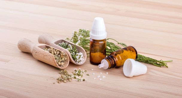 Zaradzić homeopatycznym krwawnik pospolity / homeopatyczne z krwawnika kwitnienia i dwie łyżki drewniane tła - Zdjęcie, obraz