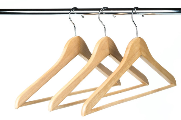 drei hölzerne Kleiderbügel auf einer Kleiderstange mit weißem Hintergrund. möglicher Kopierraum links von Kleiderbügeln. - Foto, Bild