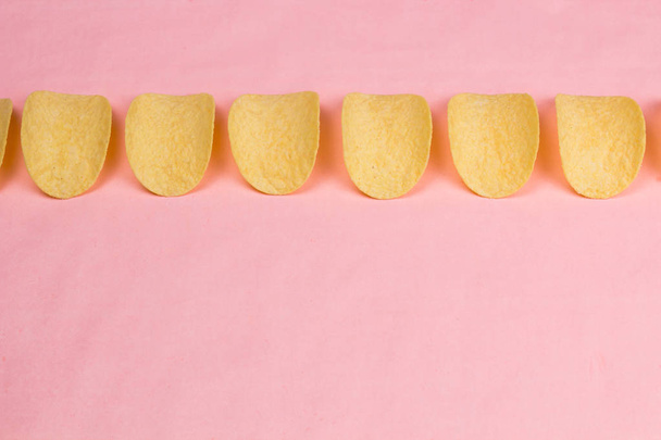 Potato chips op pastel roze achtergrond in minimalisme stijl. - Foto, afbeelding