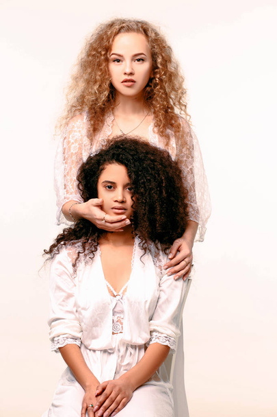 One girl closes the others eyes. Afro and Blond - Foto, afbeelding
