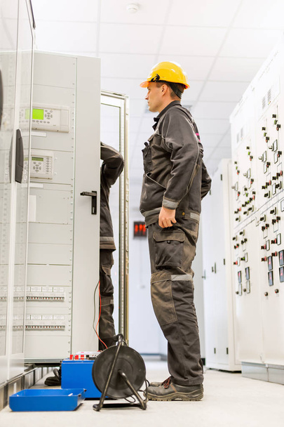 Veld servicemonteurs inspecteren systeem met relay-test set rusten - Foto, afbeelding