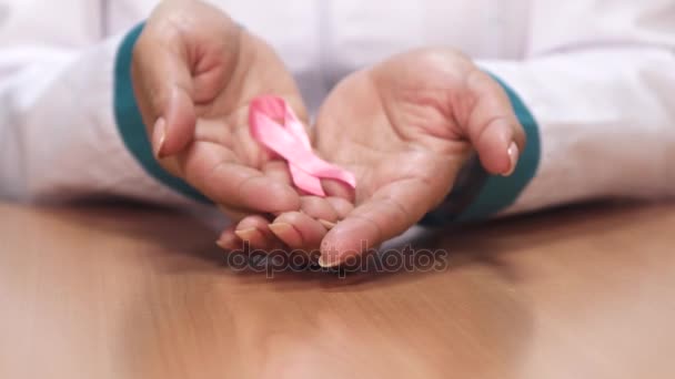 Κοντινό πλάνο του μια γυναίκα γιατρό κρατώντας ροζ κορδέλα για συνειδητοποίησης καρκίνου του μαστού - Πλάνα, βίντεο