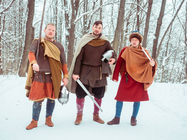 Gruppo di guerrieri armati medievali con scudi, spade, lance nella foresta invernale
 - Foto, immagini