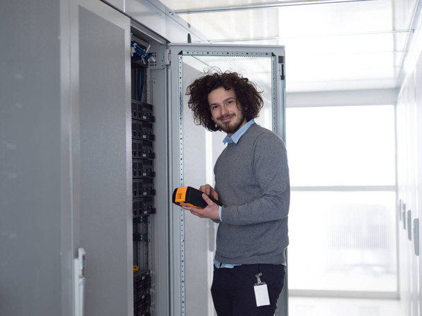 joven técnico de TI que utiliza el analizador de cable digital en el servidor en un gran centro de datos
 - Foto, Imagen