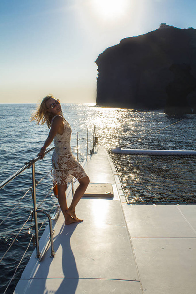 Mujer viajando en barco al atardecer entre las islas. Summer Sntorini, Grecia
 - Foto, Imagen
