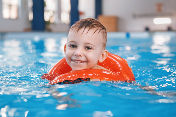 Портрет білий кавказьких дитини у плавальному басейні. Дошкільні хлопчик, навчання, щоб плавати з червоного кола кільце у воді. Здорового активного способу життя - Фото, зображення