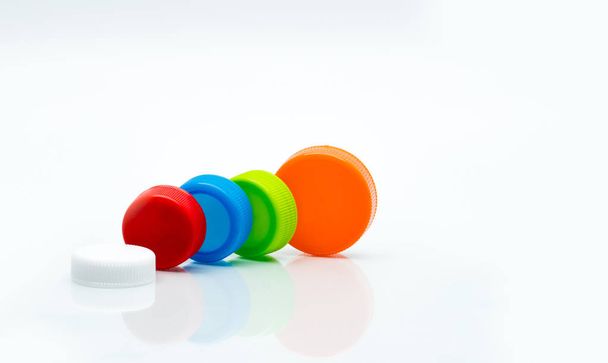 Macro shot détail de différentes tailles de blanc, vert, rouge, bleu et orange bouchons à vis ronds en plastique de couleur sur fond blanc et l'espace de copie
. - Photo, image