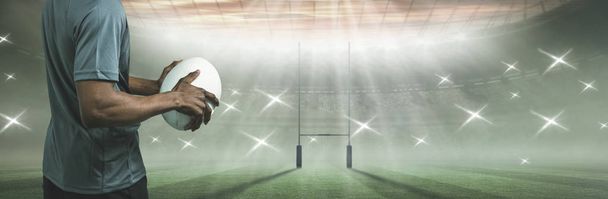 Sportsman holding rugby ball against rugby pitch - Foto, Bild