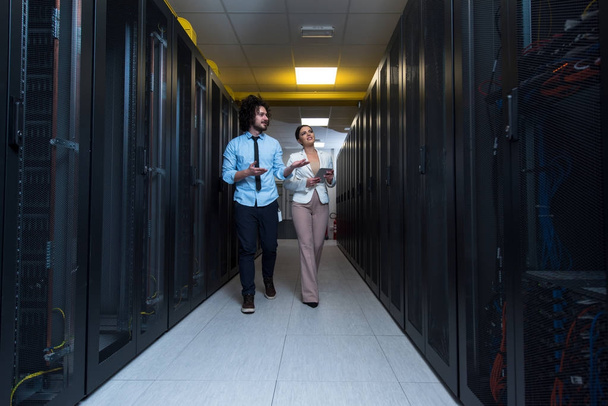 engineer showing working data center server room to female chief - 写真・画像
