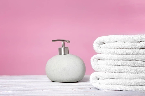 Clean towels and bottle of soap on table - Fotó, kép