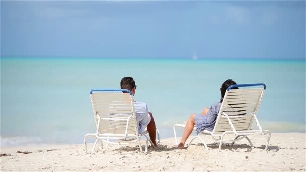 Zweiköpfige Familie entspannen auf Sonnenliegen und genießen den Meerblick und ihren Urlaub - Filmmaterial, Video