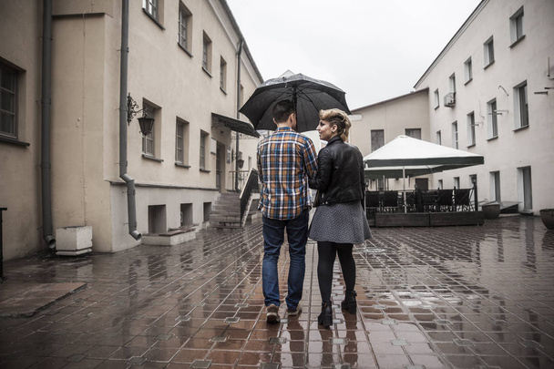 happy loving couple is under an umbrella on a city street on a rainy day - Fotografie, Obrázek