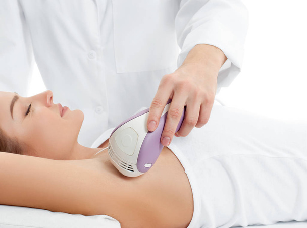 Beautician giving epilation laser treatment to woman on underarm - Foto, Imagen