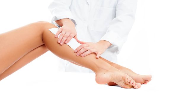 Beauty Spa. Hair removal cosmetology procedure.  Beautician waxing female legs - Fotografie, Obrázek