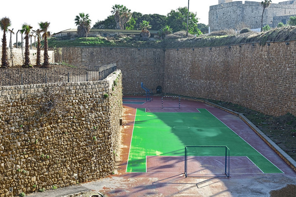 Payground construir no fosso das muralhas da cidade velha em Acre, em Israel. Vista sobre uma fortificação de uma cidade velha Akko, uma pequena cidade portuária israelense com ruínas namoro 4000 anos
 - Foto, Imagem