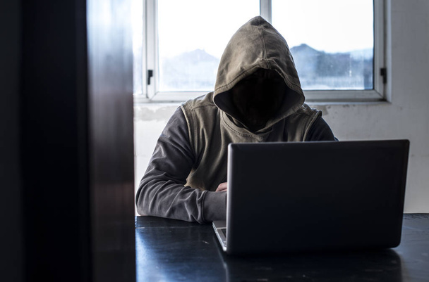 Hacker with hood. . Window in background - Φωτογραφία, εικόνα