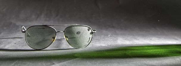 Γυαλιά ηλίου σε κοντινό πλάνο σκόνης με μια σκιά πράσινου - Φωτογραφία, εικόνα
