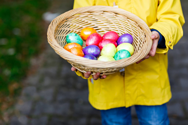 Primo piano delle mani del bambino con uova di Pasqua colorate nel cestino
 - Foto, immagini