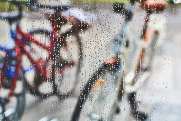 View of parked bicycles through the glass with drops of water - Φωτογραφία, εικόνα