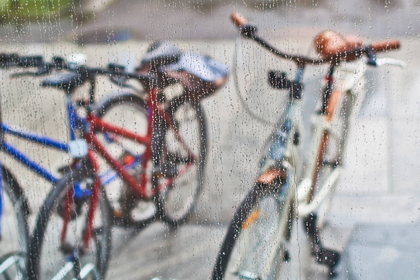 View of parked bicycles through the glass with drops of water - Φωτογραφία, εικόνα
