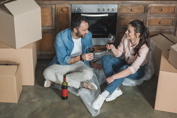 vista de ángulo alto de feliz pareja joven bebiendo vino y celebrando la reubicación
   - Foto, Imagen
