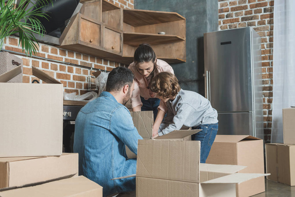 family with one child unpacking cardboard boxes in new apartment - Photo, Image