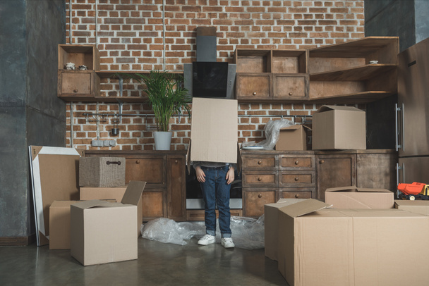 little boy standing with cardboard box on head while moving home - Φωτογραφία, εικόνα
