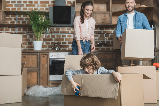 happy family with one child packing boxes while moving home  - Photo, Image