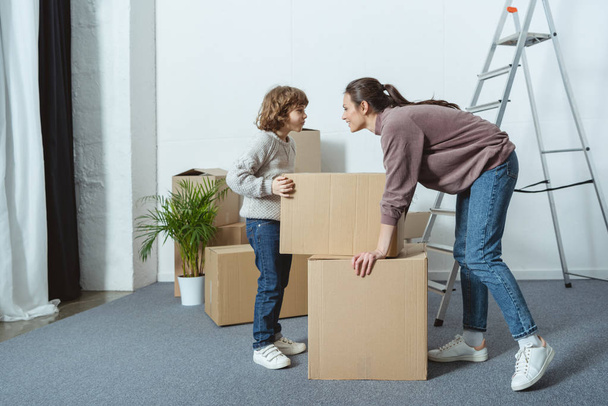 щаслива мати і син дивляться один на одного під час упаковки коробки під час переїзду
 - Фото, зображення