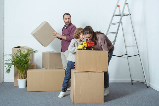 οικογένεια με ένα παιδί από χαρτόνι κουτιά συσκευασίας ενώ κινείται σπίτι  - Φωτογραφία, εικόνα
